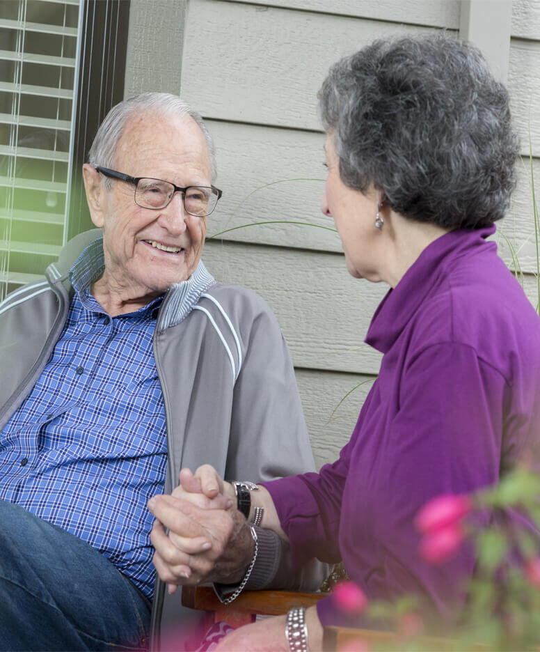 Couple sitting holding hands at Greer Gardens community