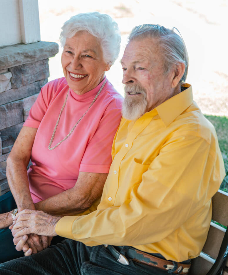 Resident couple sitting on an outdoor bench at the Whitefish community