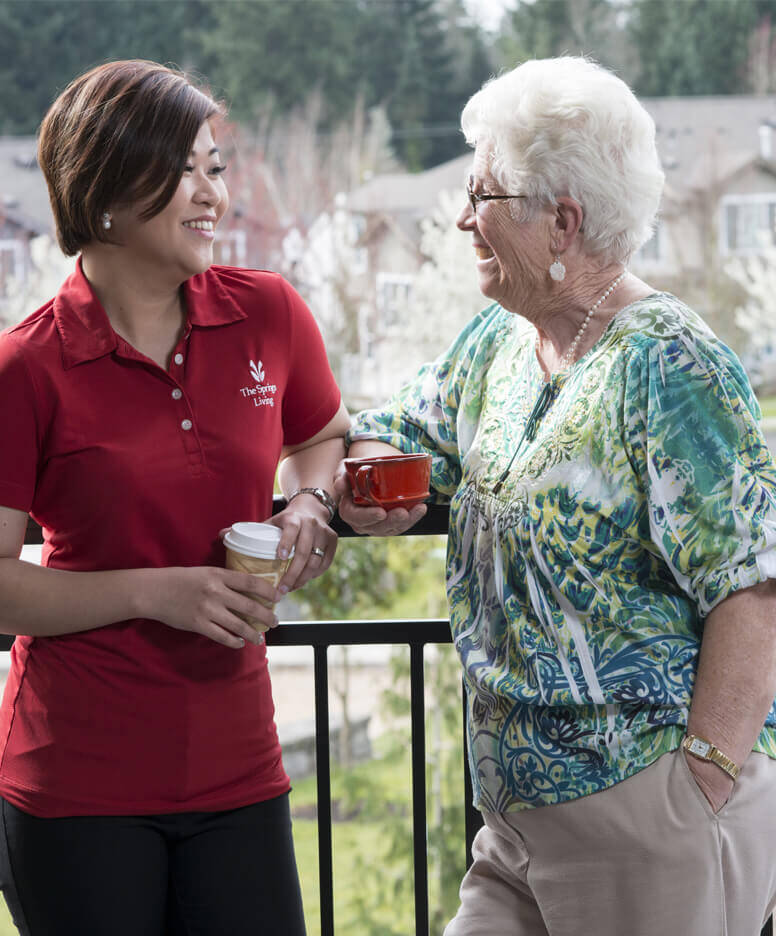 The Springs Living care giver and resident chatting outside over a cup of coffee