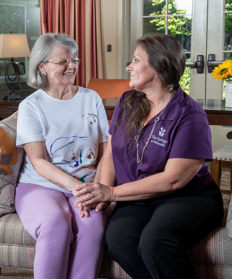 Nurse sitting with a resident at the Wilsonville community