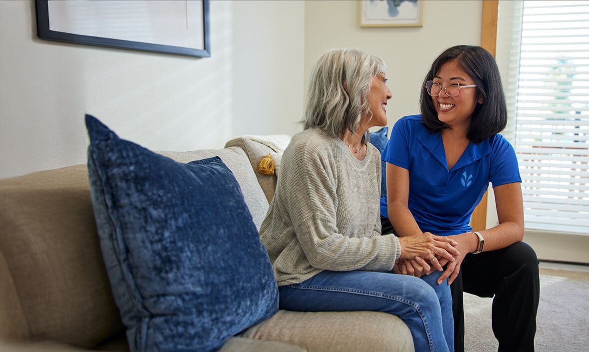 Two women sitting on a couch, holding hands