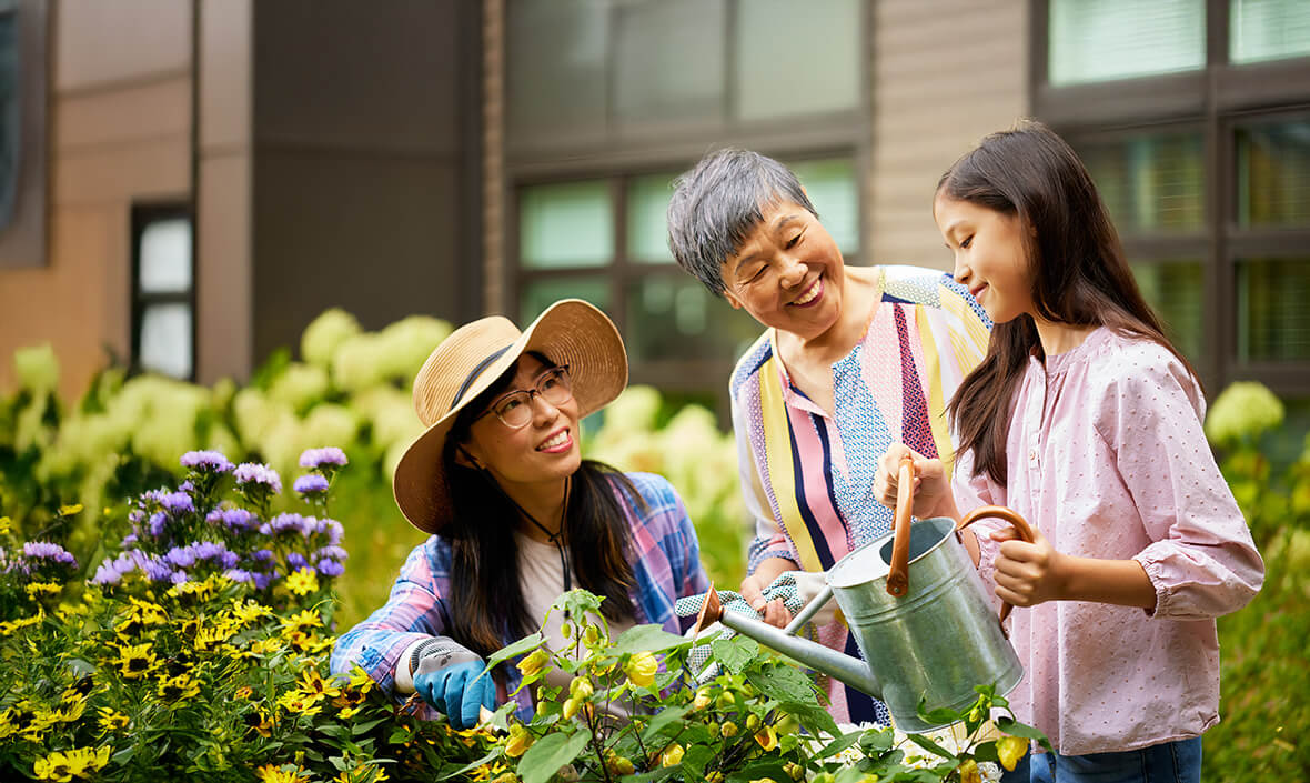 Two women and a granddaughter tending to a flower garden