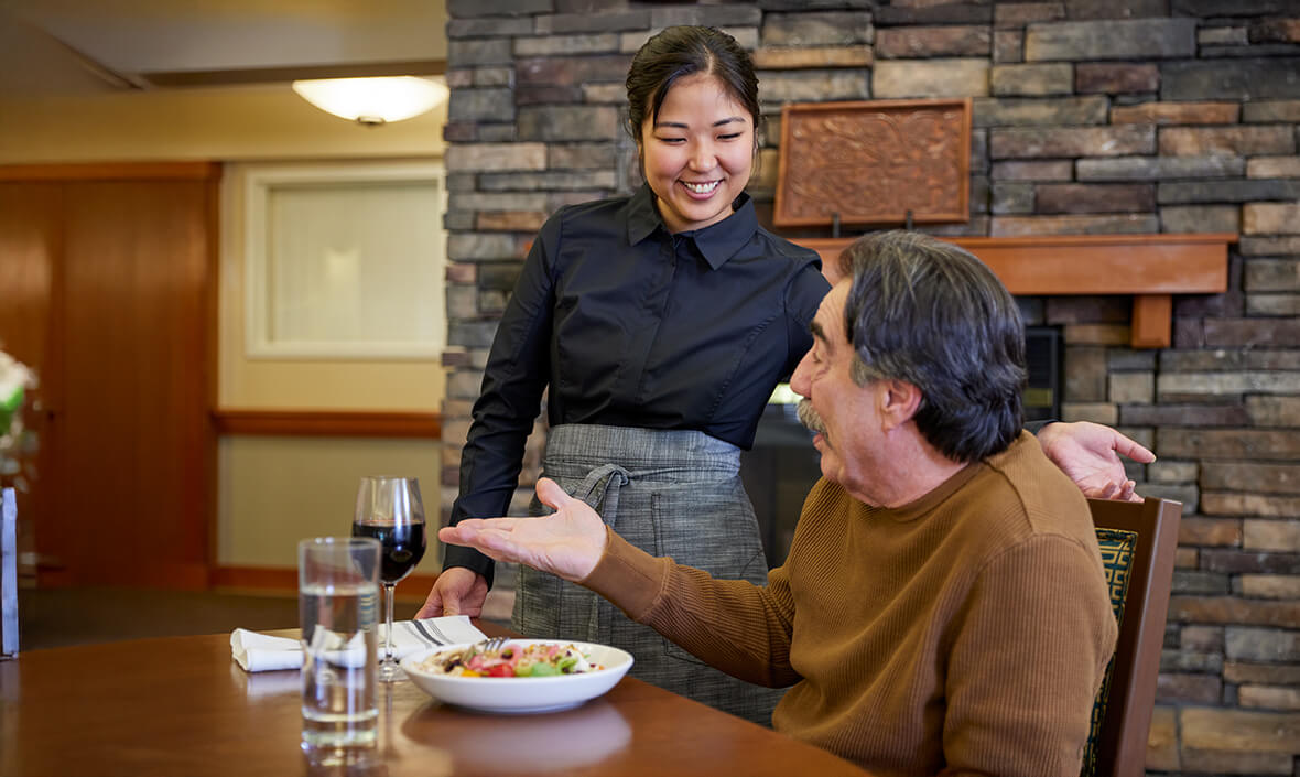 Server talking to a man eating his lunch