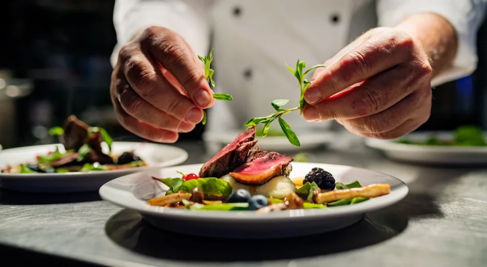 A chef topping a dish with garnish at The Springs at Sherwood in Sherwood, Oregon