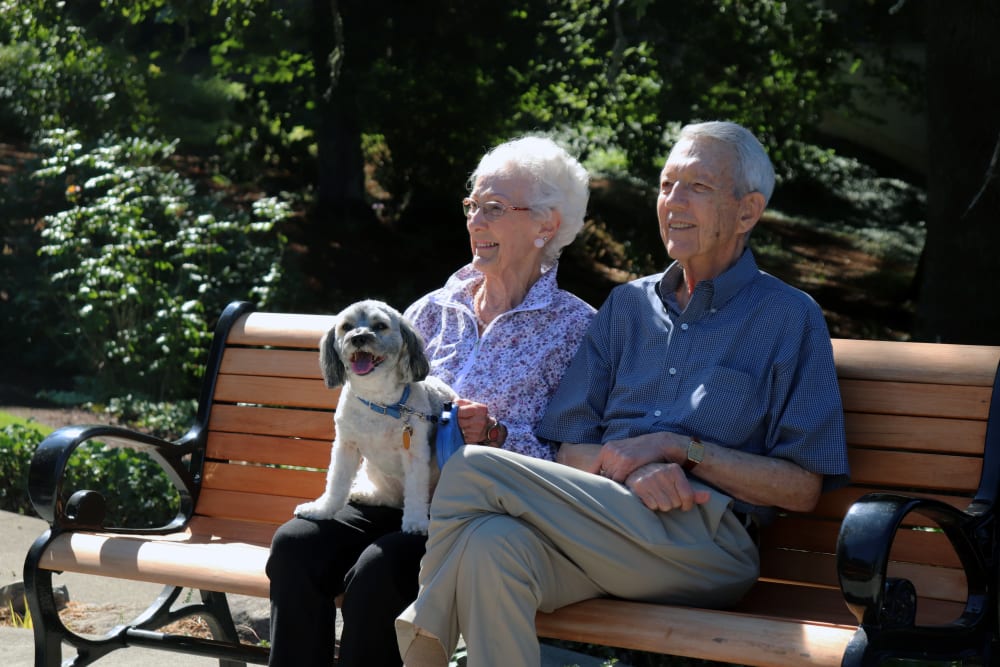 A resident couple sitting in the garden with their dog at The Springs at Carman Oaks in Lake Oswego, Oregon.