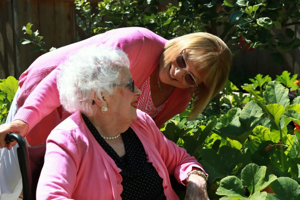 Resident and caregiver enjoying a stroll through the garden at The Springs at Carman Oaks in Lake Oswego, Oregon. 