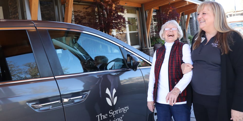 Resident with caregiver next to company vehicle at The Springs at Greer Gardens in Eugene, Oregon.