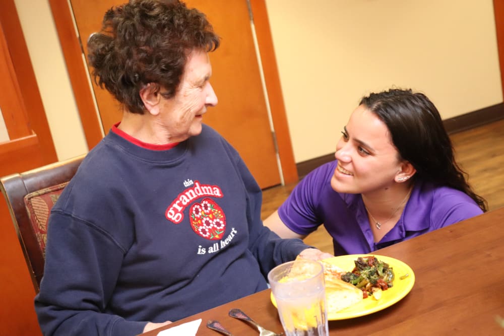 Caregiver and resident smiling at each other over a meal at The Springs at Sherwood in Sherwood, Oregon