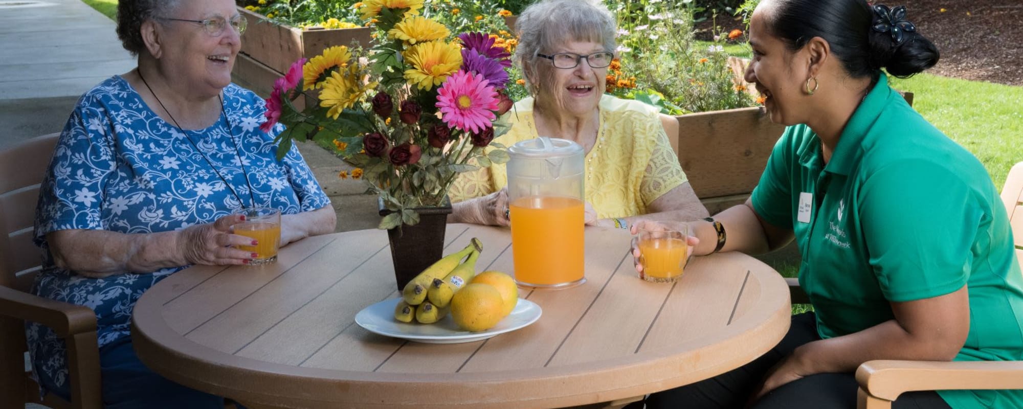 Two residents and an employee enjoying a beverage outside at The Springs at Willowcreek in Salem, Oregon