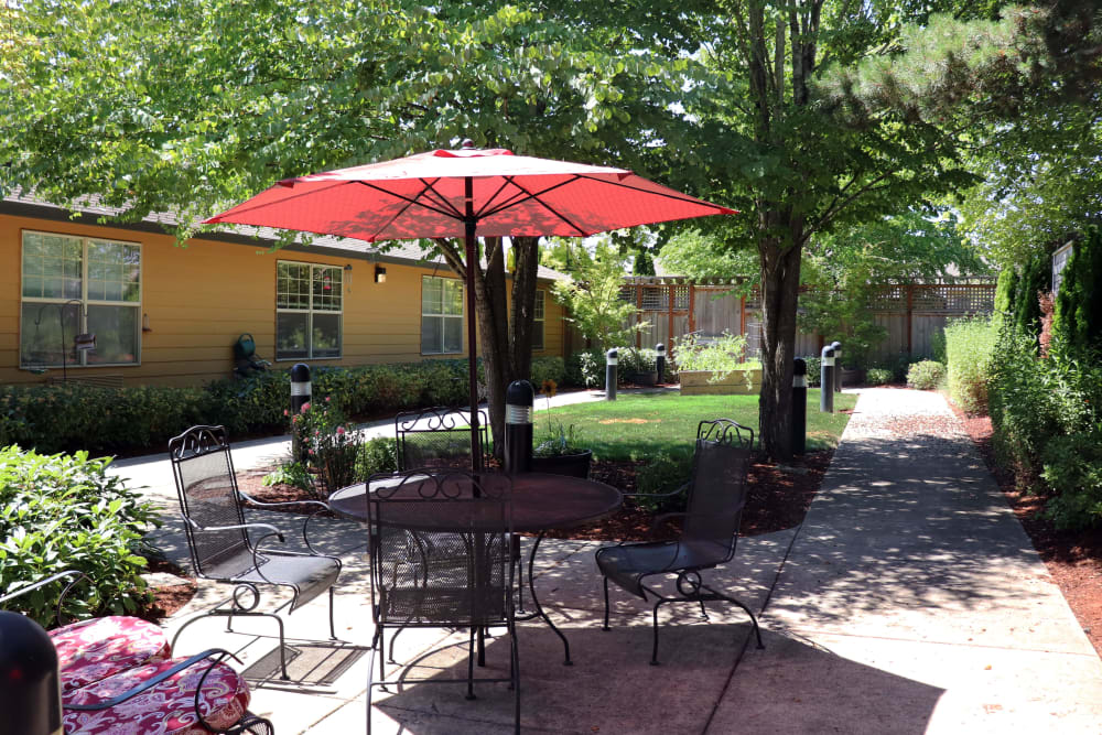 Outside patio seating on a sunny day complete with bright red umbrella at The Springs at Willowcreek in Salem, Oregon