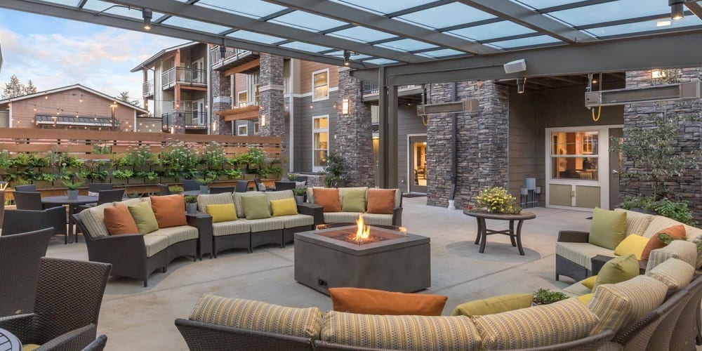 warmly lit patio with covered seating and a fire pit at The Springs at Greer Gardens in Eugene, Oregon