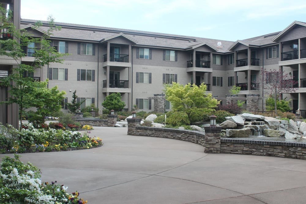 Front entrance to upscale senior living facility with stonework, pond, and foliage at The Springs at Veranda Park in Medford, Oregon