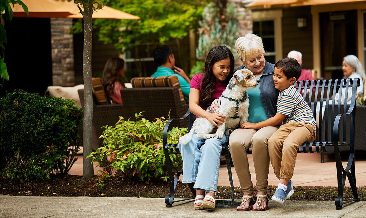 Woman sitting on a bench with two grandchildren and a dog